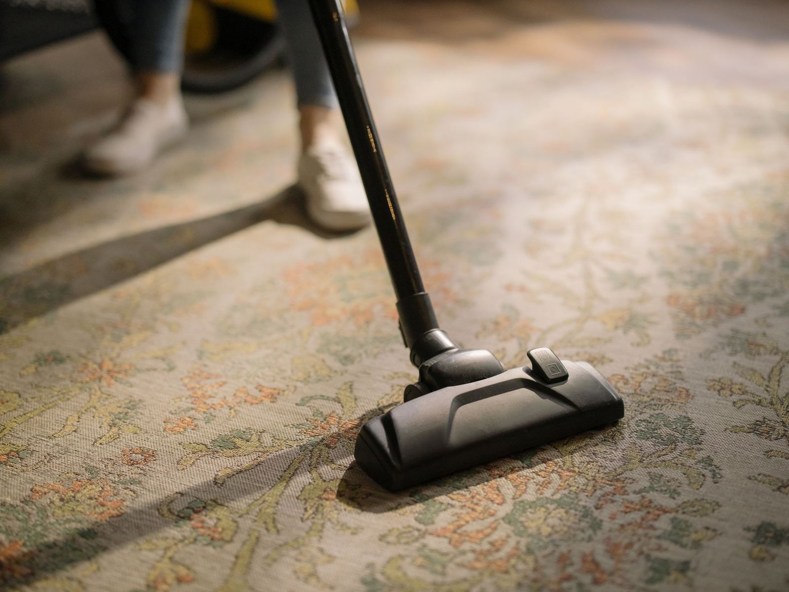 Staubsauger auf einem gemusterten Teppich im Sonnenlicht